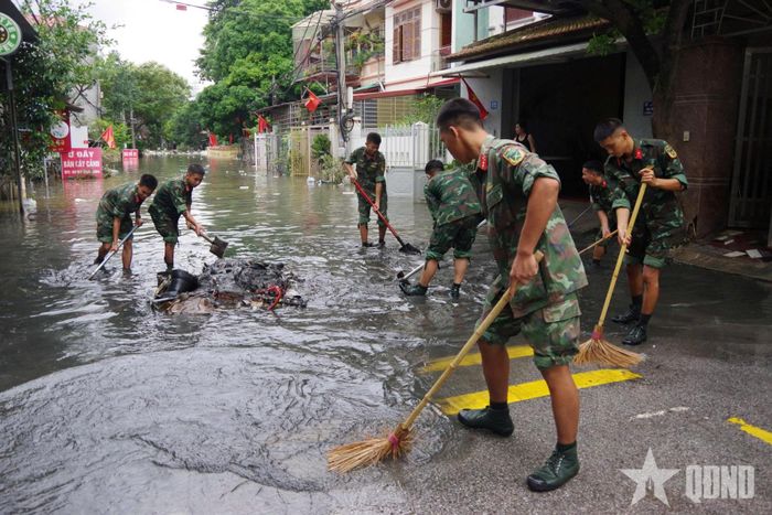 Các chiến sĩ dọn dẹp bùn rác, giúp khơi thông dòng chảy tại điểm ngập úng trên địa bàn phường Tam Thanh.