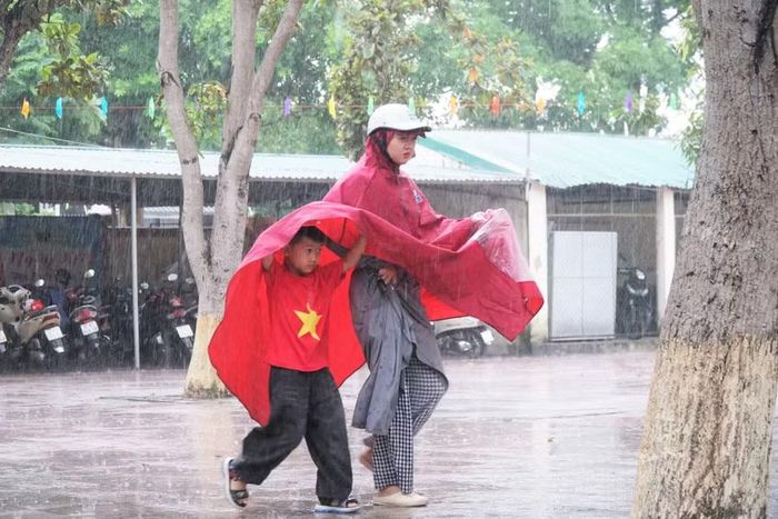 Phụ huynh và học sinh Trường Tiểu học Hưng Lộc (Vinh Lộc, Nghệ An) đội mưa đi tựu trường. Ảnh: Hồ Lài