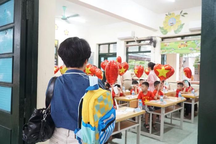 Phụ huynh đưa trẻ đến lớp và nán lại để theo dõi con được cô giáo hướng dẫn vào vị trí của mình. Ảnh: Hồ Lài
