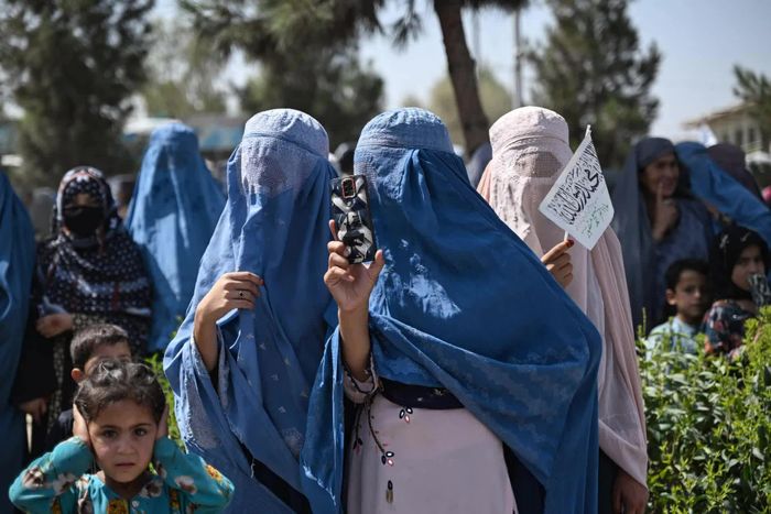 Một phụ nữ dùng điện thoại ghi lại những hoạt động kỷ niệm 5 năm Taliban trở lại nắm quyền tại Kandahar, Afghanistan. Năm năm sau ngày Taliban tiến vào Kabul, Afghanistan đã có được sự ổn định nhất định về an ninh và quyền lực, song phía sau những lễ kỷ niệm vẫn là một đất nước chật vật với khó khăn kinh tế và khủng hoảng nhân đạo. Đặc biệt, những hạn chế ngày càng nghiêm ngặt đối với phụ nữ và trẻ em gái tiếp tục phủ bóng lên đời sống xã hội, đồng thời trở thành rào cản lớn trên con đường hội nhập của Afghanistan với thế giới. (Nguồn: Al Jazeera)