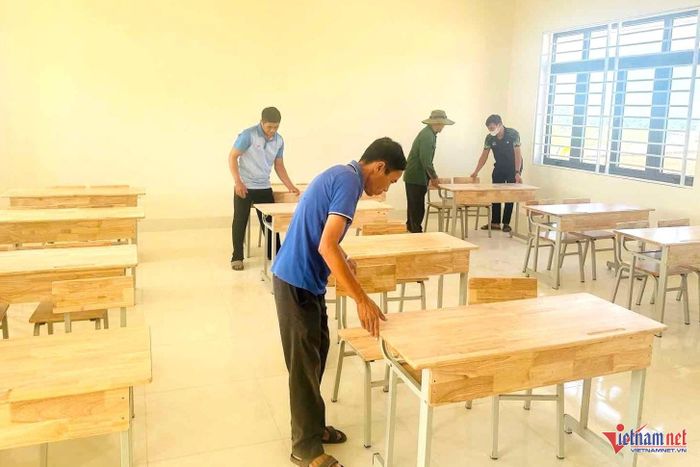 Các thầy giáo chỉnh trang bàn ghế ở khối tiểu học. Ảnh: HSC