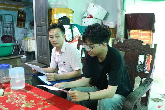 Cán bộ Phòng Giao dịch NHCSXH Cẩm Xuyên hướng dẫn em Dương Nguyễn Nhật Sang hoàn thiện hồ sơ vay vốn.