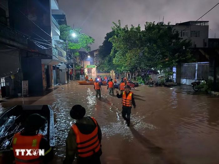 Rất đông lực lượng chức năng dùng thuyền để vào đưa các hộ dân ra khỏi vùng bị ngập tại phường Lương Văn Tri. (Ảnh: Tiến Vĩnh/TTXVN)