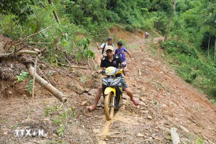 Người dân bản Na Ngân (xã Nga My, Nghệ An) vất vả khi cố gắng đi qua những điểm sạt lở trên tuyến đường Xốp Kho - Na Ngân. (Ảnh: Xuân Tiến/TTXVN)