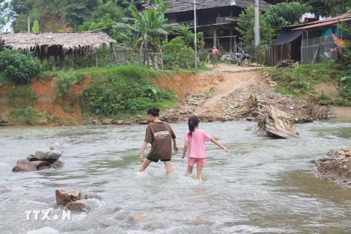 Không còn cầu tạm nối giữa 2 cụm dân cư của bản, trẻ em trong bản Na Ngân (xã Nga My, Nghệ An) vất vả khi lội qua suối Nậm Ngân để trở về nhà. (Ảnh: Xuân Tiến/TTXVN)