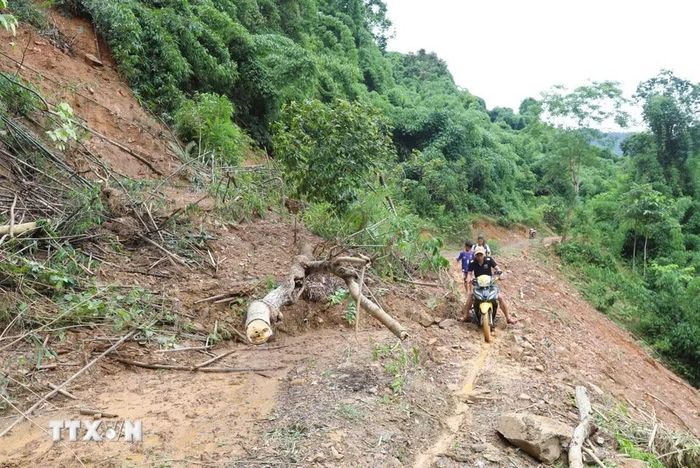 Điểm sạt lở đất đá, cây rừng phủ kín mặt đường tại dốc Co Phắc Pặp nên người dân phải men theo lối đi nhỏ sát mép vực của suối Nậm Ngân. (Ảnh: Xuân Tiến/TTXVN)