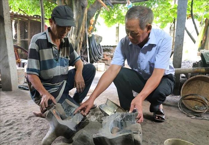 Ông Đỗ Đức Cảm (bìa trái) chia sẻ về quy trình sản xuất đồ đồng.