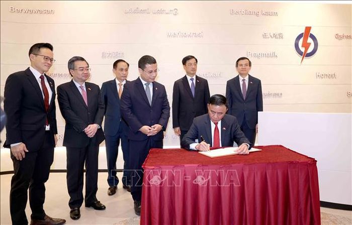 Thường trực Ban Bí thư Trần Cẩm Tú viết sổ lưu niệm tại trụ sở Đảng Hành động Nhân dân Singapore. Ảnh: Phương Hoa/TTXVN