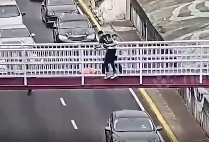 Nam thanh niên ôm chặt lấy người đàn ông đang có ý định tự tử. Ảnh cắt từ clip/Newsflare