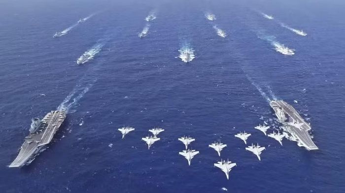 Tàu Liêu Ninh (trái) và tàu Sơn Đông (phải) với các tiêm kích hạm J-15 bay phía trên. Ảnh: TWZ.