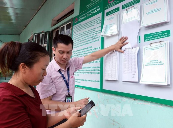 Tổ trưởng Tổ Tiết kiệm và vay vốn đối chiếu danh sách hộ vay được số hóa với danh sách niêm yết công khai tại điểm giao dịch xã Bản Lầu, Lào Cai. Ảnh: Trần Việt - TTXVN