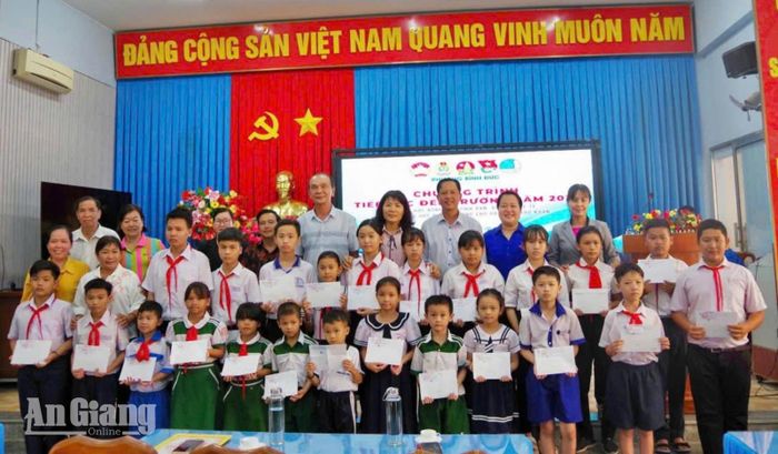 Lãnh đạo phường Bình Đức và nhà hảo tâm trao học bổng tiếp sức đến trường cho học sinh trước thềm năm học mới. Ảnh: PHƯƠNG LAN