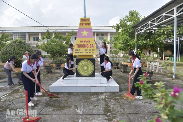 Giáo viên và học sinh Trường THCS Đông Yên vệ sinh sân trường. Ảnh: ĐẶNG LINH.
