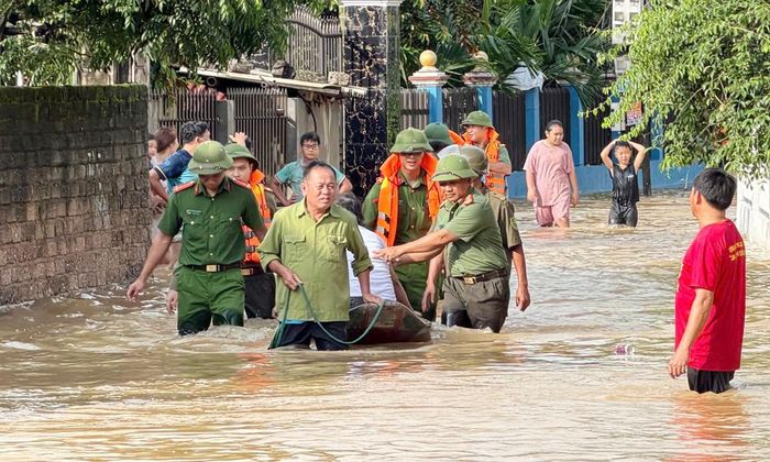  Lực lượng công an hỗ trợ đưa người dân vùng lũ ở xã Tiên Lục đến nơi an toàn.  