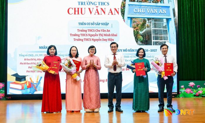 Bí thư Đảng ủy phường Thanh Khê Nguyễn Thành Tiến (thứ 3, phải sang), Chủ tịch UBND phường Trần Tường Vân (thứ 3, trái sang) trao quyết định và tặng hoa Ban Giám hiệu Trường THCS Chu Văn An. Ảnh: NGỌC HÀ