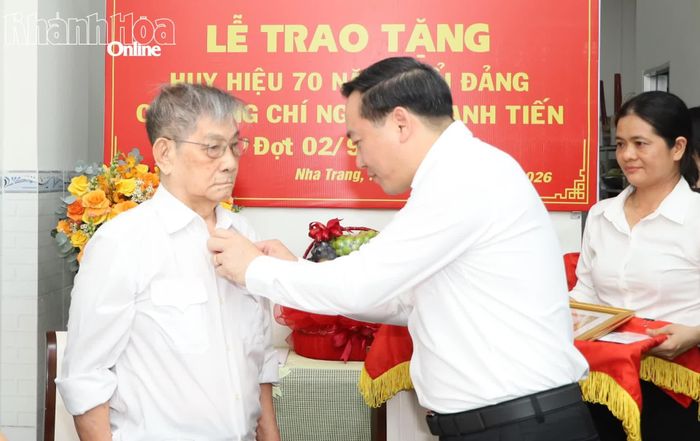 Phó Bí thư Thường trực Tỉnh ủy Hồ Xuân Trường gắn Huy hiệu 70 năm tuổi Đảng lên ngực áo đảng viên Nguyễn Mạnh Tiến.