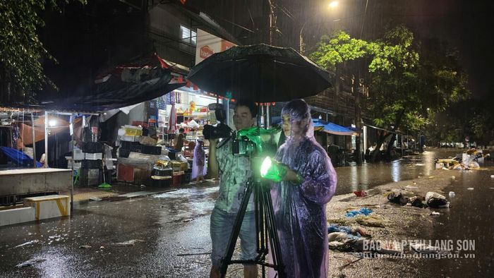 Phóng viên Hoàng Huấn và Hoàng Yến (Báo và PTTH Lạng Sơn) tác nghiệp trong mưa bão ghi nhận thông tin tại khu vực chợ Giếng Vuông (phường Kỳ Lừa)