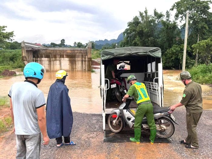 Lực lượng Công an xã Mường Bi cảnh báo người dân không đi vào khu vực nước sâu và trực tiếp hỗ trợ đưa phương tiện và người dân qua những đoạn đường ngập, bảo đảm an toàn.