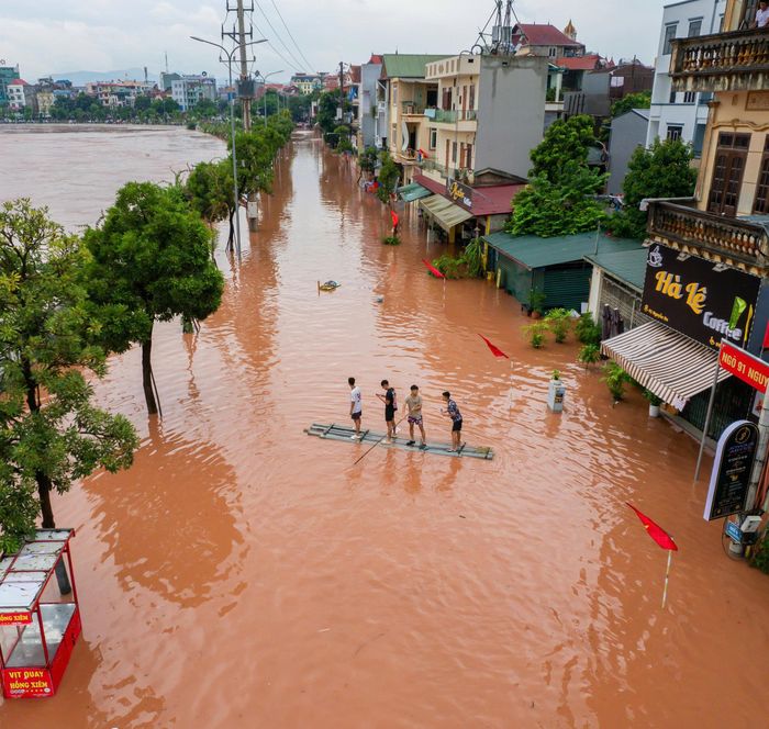 Người dân sống gần sông Kỳ Cùng phải di chuyển bằng thuyền, bè qua những khu vực nước ngập. (Ảnh: Trần Hùng).