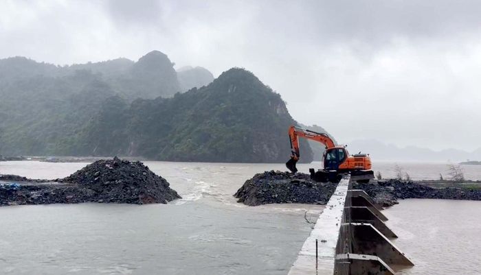 Lực lượng chức năng sử dụng máy cẩu mở rộng tuyến đê, tạo dòng thoát nước ra biển, góp phần giảm ngập tại khu vực bị ảnh hưởng. (Ảnh: Xuân Thủy)
