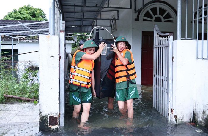Lực lượng chức năng vận chuyển đồ đạc cho người dân đến nơi cao hơn để tránh thiệt hại. (Ảnh: Xuân Thủy)