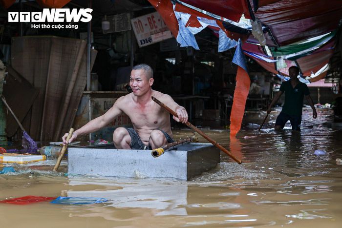 Tại những vị trí nước còn dâng cao, tiểu thương phải sử dụng bè tự chế để tiếp cận các ki-ốt.