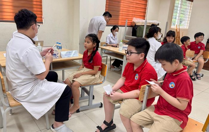 Học sinh lần lượt thực hiện các nội dung khám sức khỏe theo hướng dẫn của đội ngũ y, bác sĩ. Ảnh: Võ Giang