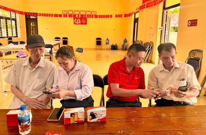 Thành viên các tổ chuyển đổi số tại xã Thuận An hướng dẫn người dân quét mã QR tham gia Nhóm chat cộng đồng trên ứng dụng iHanoi. Ảnh: Vân Thư