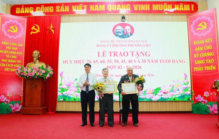 Bí thư Đảng ủy, Chủ tịch HĐND phường Phương Liệt Nguyễn Minh Tiến trao Huy hiệu 70 năm tuổi Đảng tặng 2 đảng viên lão thành. Ảnh: HL