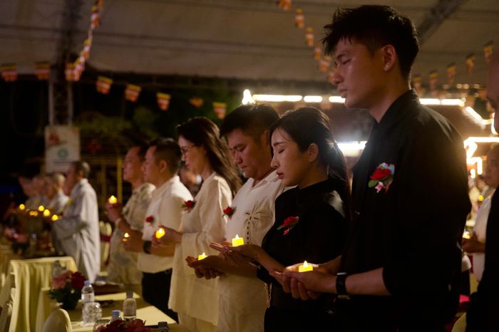 Giữa muôn ánh nến lung linh, màu hoa trên ngực áo như chiếc gương soi chiếu phận người: hoa đỏ cho ai còn đủ cha mẹ, hoa hồng nhạt cho người mất cha hoặc mẹ, và hoa trắng nghẹn ngào dành cho những ai đã mất đi cả hai điểm tựa lớn nhất đời.