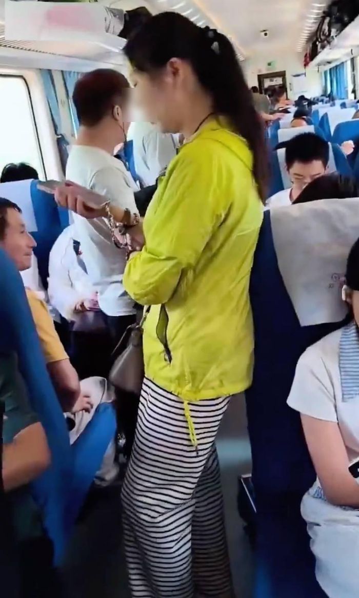 Người phụ nữ chấp nhận đứng trên hành trình của chuyến tàu sau khi nhờ nhân viên trên tàu can thiệp nhưng không được. Ảnh: Sina.