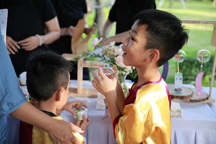 Trong hành trình ấy, “Chuông gió ước nguyện” trở thành một trong những điểm dừng giàu cảm xúc. Các em nhỏ cùng ngồi lại, tự tay trang trí những chiếc chuông gió và viết lên đó lời chúc, điều ước dành cho người thân. Đúng với tinh thần báo hiếu của mùa Vu Lan, có những bạn nhỏ lần đầu nắn nót viết một lời chúc sức khỏe cho ông bà và cha mẹ, cũng là lần đầu hiểu rằng biết ơn, yêu thương đều có thể nói ra thành lời. Nguyện ước của các con có thể khác nhau, song đều gặp nhau ở một điều giản dị: Mong những người mình yêu thương luôn bình an và phút giây sum vầy nối dài mãi.