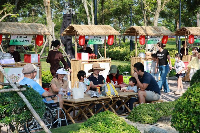 Hành trình tiếp tục nối dài qua khu ẩm thực - điểm đến để cả nhà cùng dừng chân nạp năng lượng sau những giờ vui chơi sôi nổi. Rất nhiều gian hàng từ gánh chè dân gian, kim sa lấp lánh, cuốn là ghiền đến ăn vặt tuổi thơ, trạm giải khát… kết hợp tạo nên “bản đồ ẩm thực” nhiều màu sắc. Đặc biệt, việc mua món ăn bằng những chiếc lá được thiết kế riêng cho sự kiện mang đến trải nghiệm thú vị, đồng thời gợi nhớ nét văn hóa mộc mạc, gần gũi của phiên chợ quê.