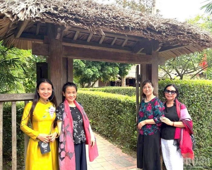 Du khách chụp ảnh lưu niệm bên cái cổng bình dị của ngôi nhà tuổi thơ Đại tướng. (Ảnh: HƯƠNG GIANG)