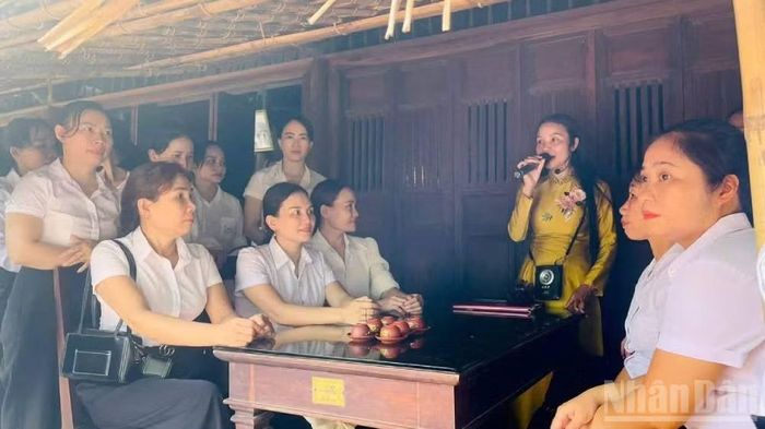 Các đoàn khách lưu lại bên hiên nhà để nghe hướng dẫn viên Khu lưu niệm Đại tướng Võ Nguyên Giáp giới thiệu về tuổi thơ và gia đình Đại tướng. (Ảnh: HƯƠNG GIANG)