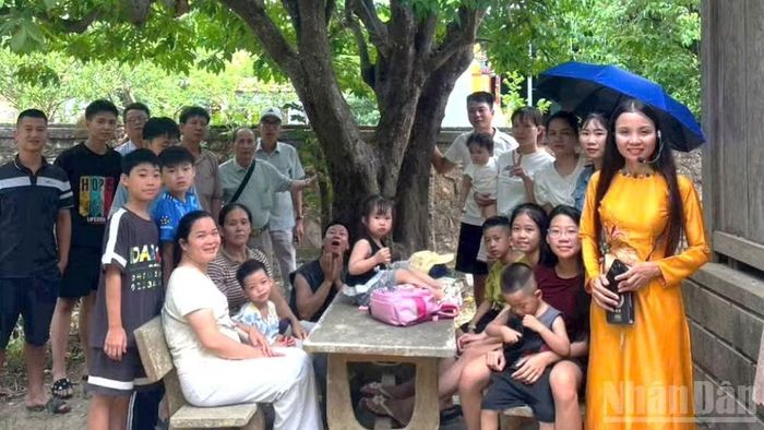 Nhiều du khách các thế hệ thích thú khi được chụp ảnh dưới gốc cây khế có tuổi đời hơn 1 thế kỷ trong khuôn viên Nhà lưu niệm Đại tướng. (Ảnh: HƯƠNG GIANG)