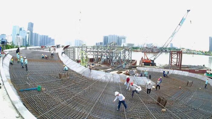 Công nhân đang đẩy nhanh tiến độ thi công trên công trường cầu đi bộ trong lúc chờ nhịp chính vòm thép lai dắt về khu vực công trình. (Ảnh: VÕ LÊ)