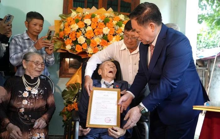 Đại tướng Nguyễn Trọng Nghĩa, Chủ nhiệm Tổng cục Chính trị Quân đội nhân dân Việt Nam trao quyết định tặng Huy hiệu 80 năm tuổi Đảng cho đảng viên Nguyễn Anh Hùng, sinh năm 1923, ở đội 2, thôn Phú Lộc, xã Nam Gianh, tỉnh Quảng Trị. (Ảnh: H.M)