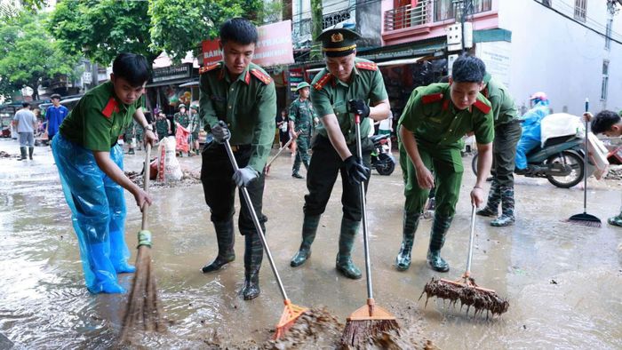 Lực lượng chức năng hỗ trợ người dân khắc phục bùn đất tại các điểm ngập khi nước lũ rút dần, ngày 24-8. Ảnh: Công an tỉnh Lạng Sơn