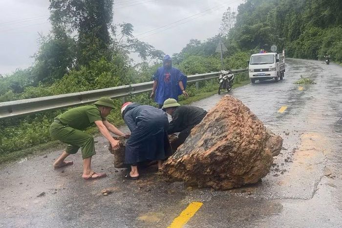Lực lượng chức năng xã Nậm Cắn thu dọn đất đá lăn xuống Quốc lộ 7.
