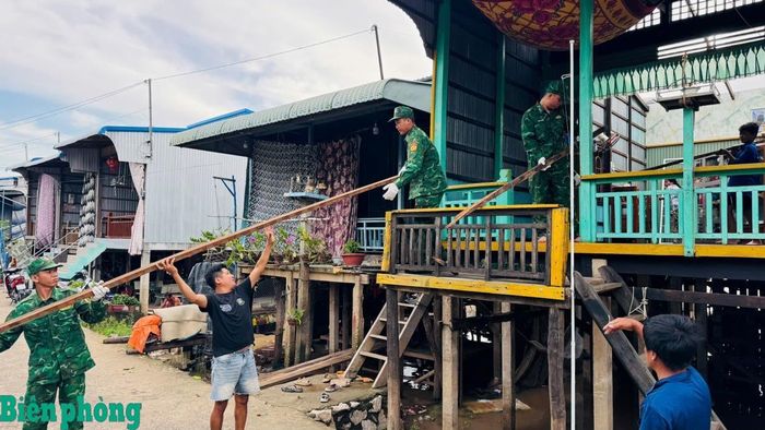 Cán bộ, chiến sĩ Đồn Biên phòng cửa khẩu Vĩnh Hội Đông phối hợp với người dân sửa chữa căn nhà bị tốc mái do dông lốc tại ấp Vĩnh Hòa, xã An Phú. Ảnh: Đình Phương