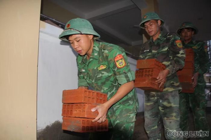 Trên công trường, màu áo xanh của người lính hòa cùng sắc áo của những người thợ. Mỗi người một phần việc, từ vận chuyển vật liệu, hoàn thiện lớp học đến chỉnh trang khuôn viên, nhưng tất cả cùng chung một mục tiêu: Đưa ngôi trường mới về đích đúng hẹn, để những đứa trẻ vùng biên sớm được bước vào lớp học khang trang, bắt đầu một năm học mới với những ước mơ phía trước (ảnh Trần Hiền)