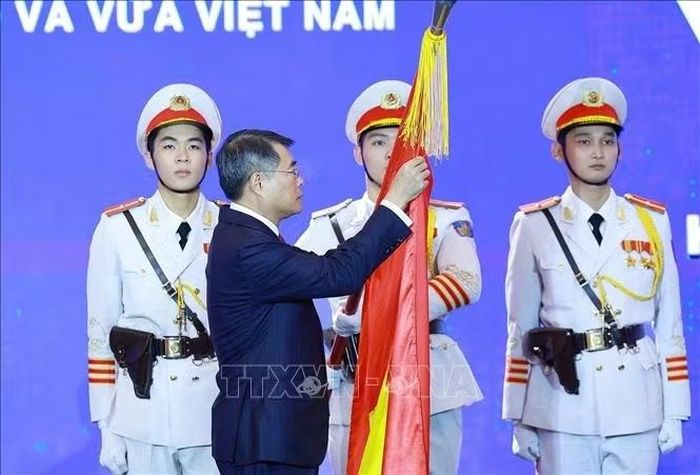 Thủ tướng Lê Minh Hưng gắn Huân chương Lao động hạng Nhất lên Cờ truyền thống của Hiệp hội Doanh nghiệp nhỏ và vừa Việt Nam. Ảnh: Dương Giang/TTXVN