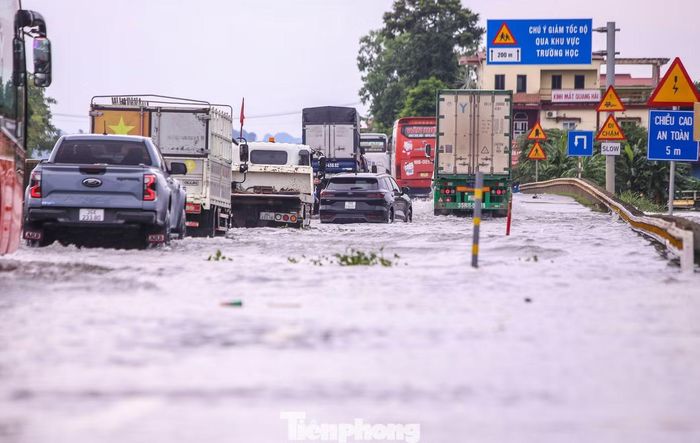 Các phương tiện nối đuôi nhau, nhích từng mét qua vị trí ngập để tránh chết máy và đảm bảo an toàn. Trong khi một số xe phải dừng lại giữa dòng nước khi bị chết máy.
