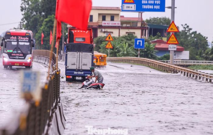 Nhiều ﻿xe máy cố vượt qua đoạn đường ngập bị chết máy. Mỗi khi có ô tô tải chạy qua tạo thành làn sóng mạnh, xô ngã người và phương tiện giữa dòng nước.