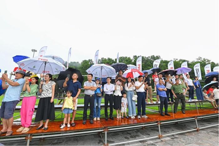  Khán giả đội mưa đứng trên khán đài cổ vũ các tay lái. 