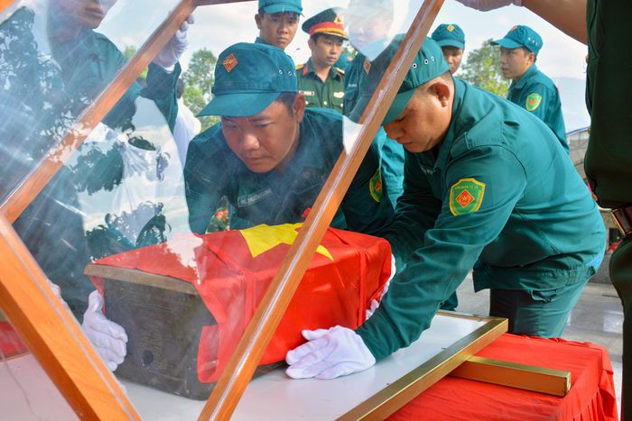 Cán bộ, chiến sĩ lực lượng vũ trang cẩn trọng kiểm tra, sắp xếp các hòm chứa hài cốt liệt sĩ trước khi di chuyển về Nghĩa trang liệt sĩ Hòn Dung. Ảnh: Xuân Ngọc