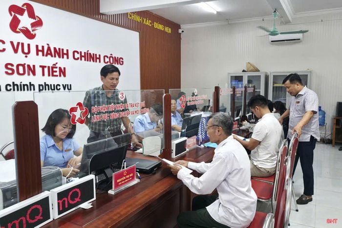 Ông Trần Học ở thôn Hòa Bình (ngồi giao dịch đầu tiên) hài lòng với thái độ phục vụ và tiến độ xử lý hồ sơ của đội ngũ cán bộ xã sau khi thực hiện chính quyền địa phương hai cấp.