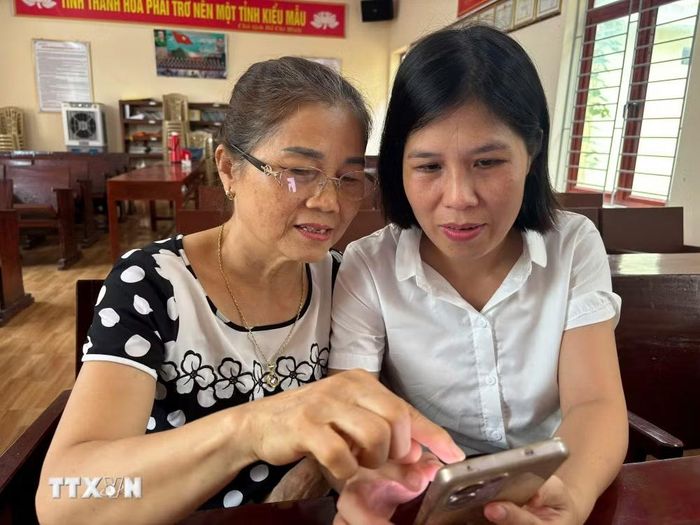 Bí thư chi bộ hướng dẫn các đảng viên sử dụng Sổ tay đảng viên điện tử. (Ảnh: Khiếu Tư/TTXVN)