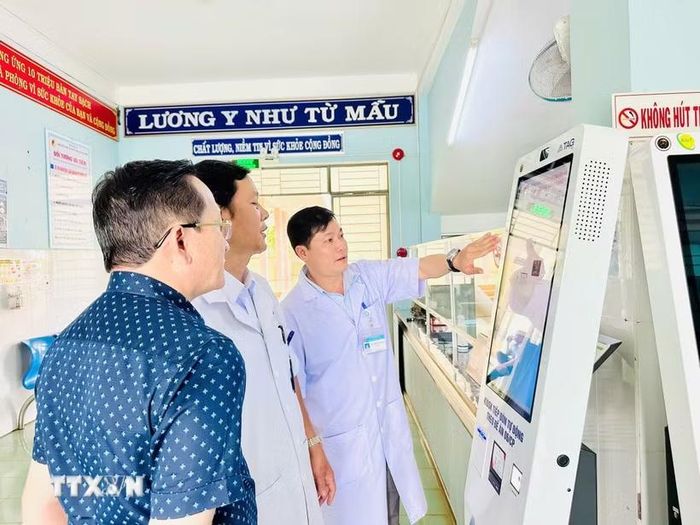 Cán bộ y tế hướng dẫn vận hành ki-ốt thông minh tại cơ sở y tế. (Ảnh: Quang Thái/TTXVN)